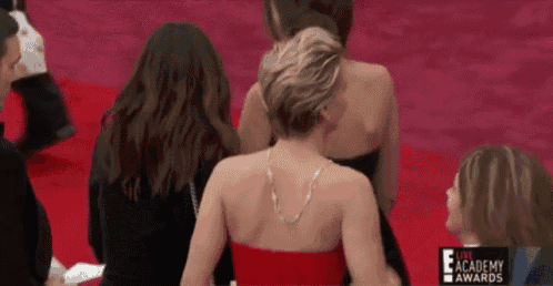 a woman in a red dress is sitting on a red carpet at the live academy awards ..
