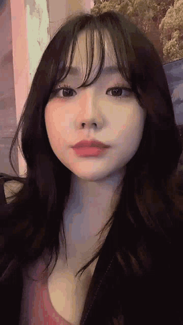 a close up of a woman 's face with a pink shirt on