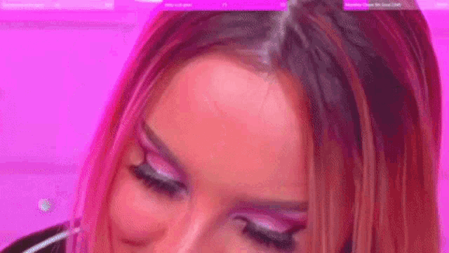 a close up of a woman 's face with pink eye shadow on a pink background .