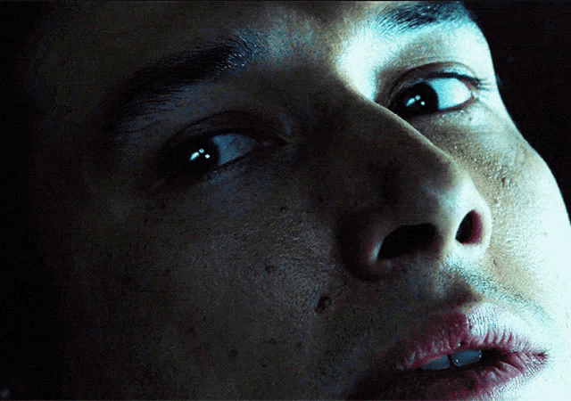 a close up of a man 's face with a blue light shining on his eye