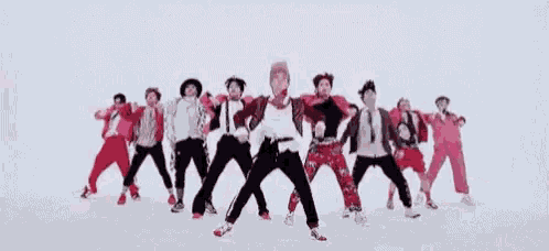 a group of young men are sitting on the floor and dancing in front of a white background .
