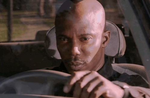 a man with a beard is driving a car and looking out the window