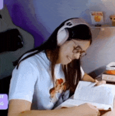 a woman is wearing headphones and reading a book .