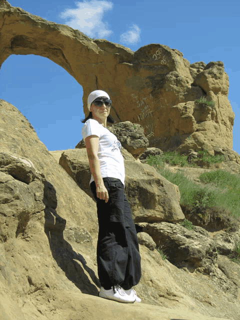 a woman standing in front of a rock formation with graffiti on it that says ' i love you '