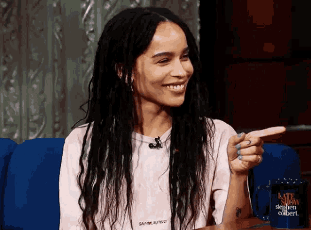 a woman wearing a saint laurent shirt is smiling and pointing at something