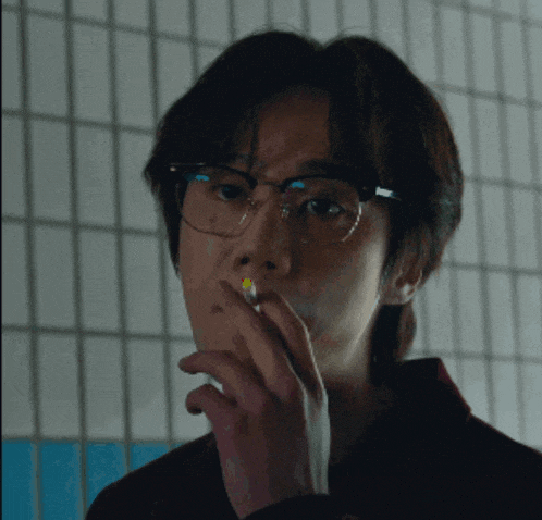 a man wearing glasses and smoking a cigarette