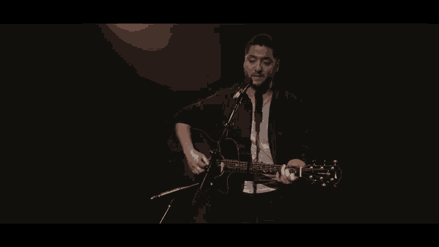 a man playing a guitar in front of a microphone