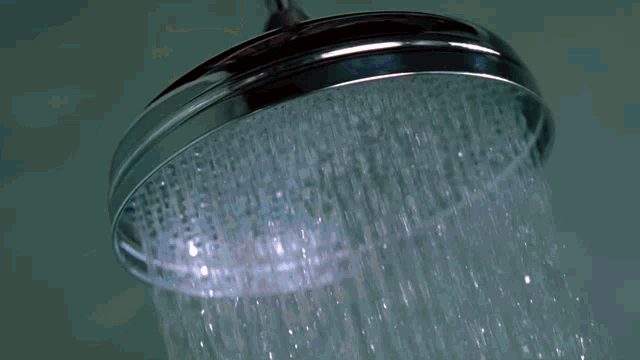 a woman in a white tank top is standing in a shower
