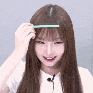 a woman with long brown hair is holding a green comb in her hand