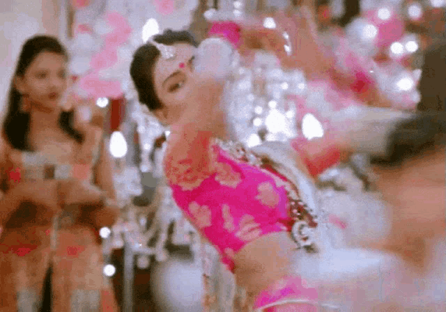 a woman in a pink blouse is dancing in a room