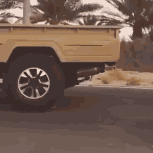 a yellow truck is parked on the side of the road in the desert .