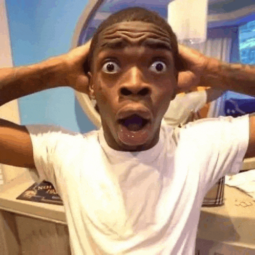 a man in a white shirt is making a funny face while holding his head .