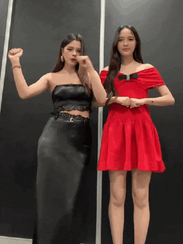 two women standing next to each other one in a red dress and the other in a black dress