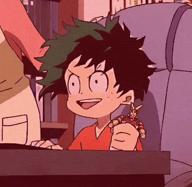 a cartoon character is sitting at a table holding a toy and smiling .