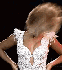 a woman in a white dress is standing on a stage with her hair in the air .