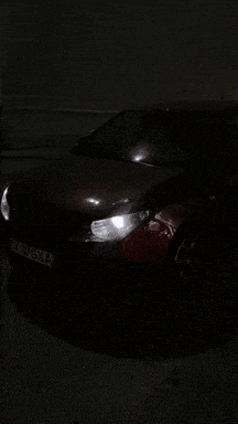a red car is parked in a dark parking lot with a license plate that says 973ka