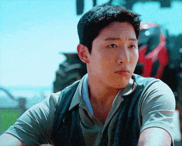 a man with a serious look on his face is sitting in front of a tractor