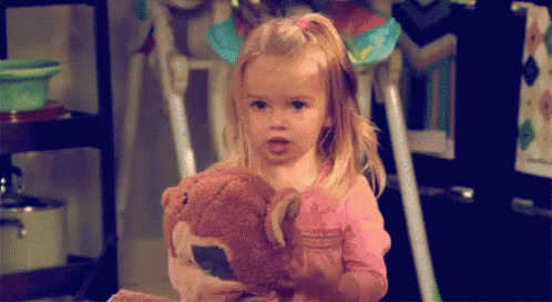 a little girl is holding a stuffed animal in her hands