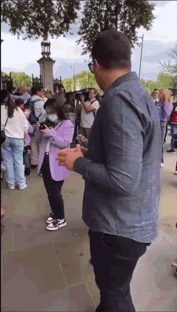 a man is standing next to a woman wearing a purple jacket taking a picture .