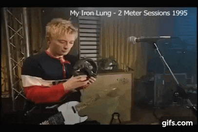 a man is playing a guitar and singing into a microphone in a room .