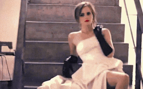 a woman in a wedding dress is sitting on a set of stairs .
