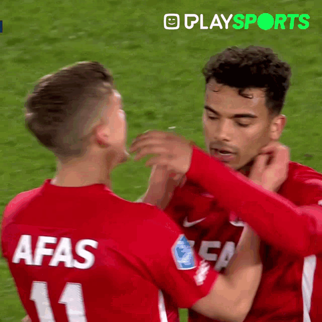 a soccer player with afas on the back of his jersey is hugging another player