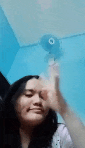 a woman is making a funny face while holding a fan .