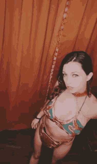 a woman in a bikini takes a selfie in front of a curtain