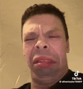 a man is making a funny face with his eyes closed and a glass of water in his mouth .