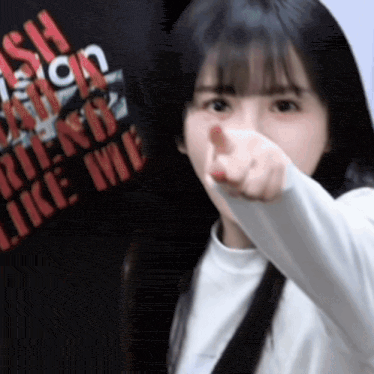 a girl pointing at the camera with a shirt that says " i 'm a bitch " on it