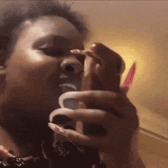 a woman with long nails is brushing her teeth while wearing a bandana