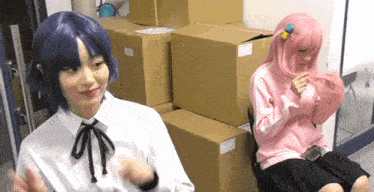 two girls in wigs are sitting next to each other in front of boxes .