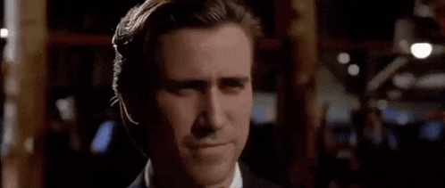 a man in a suit and tie is smiling in a dark room .