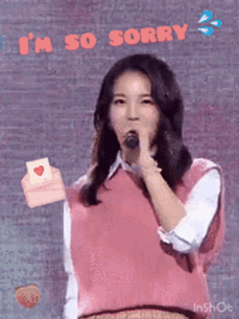 a woman in a pink vest is singing into a microphone with the words i 'm so sorry behind her