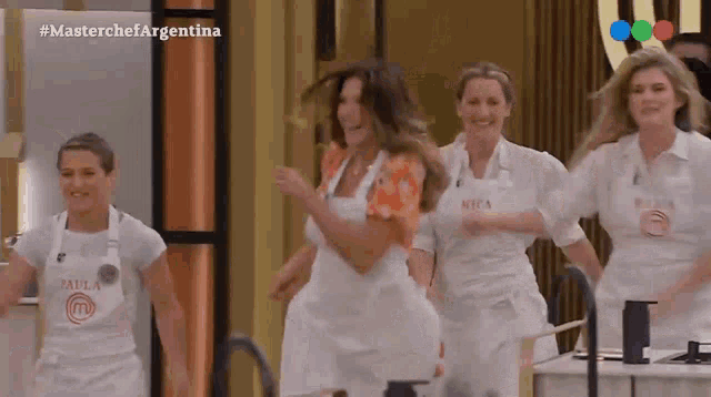 a group of women wearing aprons are dancing on a television show called masterchef argentina .