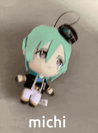 a stuffed doll with green hair and purple eyes is sitting on a table with the name michi written on it .