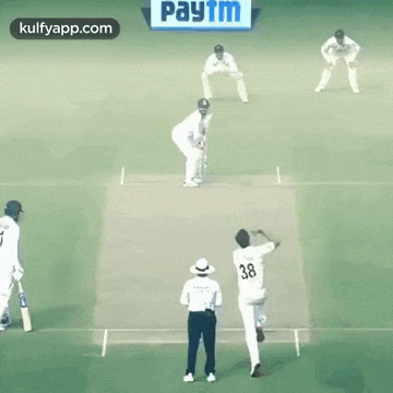a group of cricket players are playing a game of cricket on a green field .