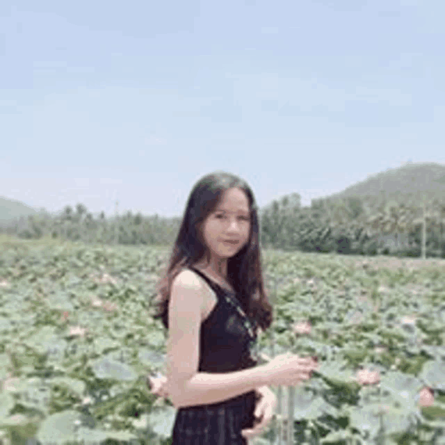 a young woman is standing in a field of lotus flowers .