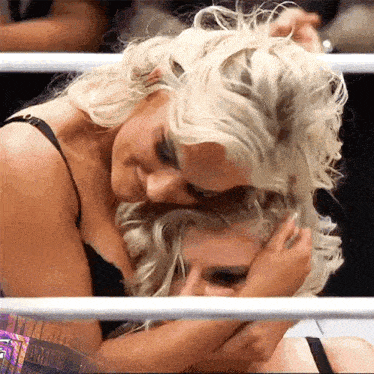 two women are hugging each other in a ring .