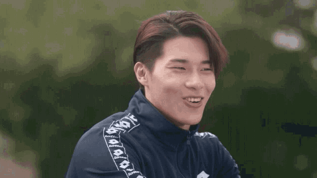 a young man is making a funny face while wearing a blue jacket with the word lotto on the side .