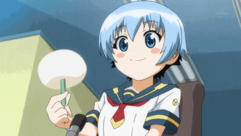 a girl in a sailor uniform is holding a fan and smiling for the camera while sitting in a chair