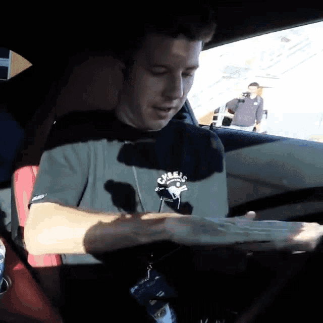 a man sitting in a car wearing a shirt that says cybe 's