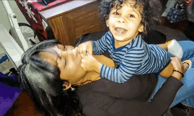 a woman is holding a child in her arms and the child is laughing