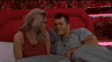 a man and a woman are laying on a bed and looking at each other .