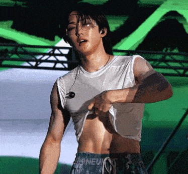 a man in a white tank top shows off his muscles