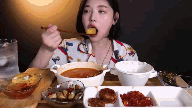 a woman is eating a bowl of soup with a spoon in her mouth