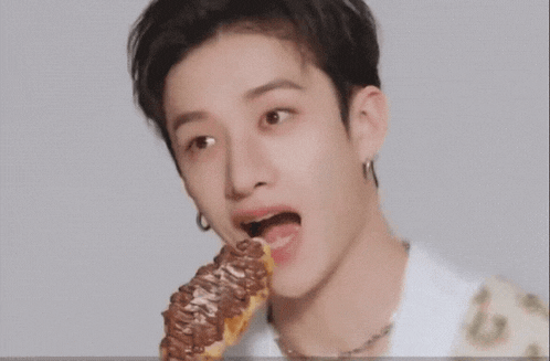 a young man is eating a waffle with chocolate sauce .