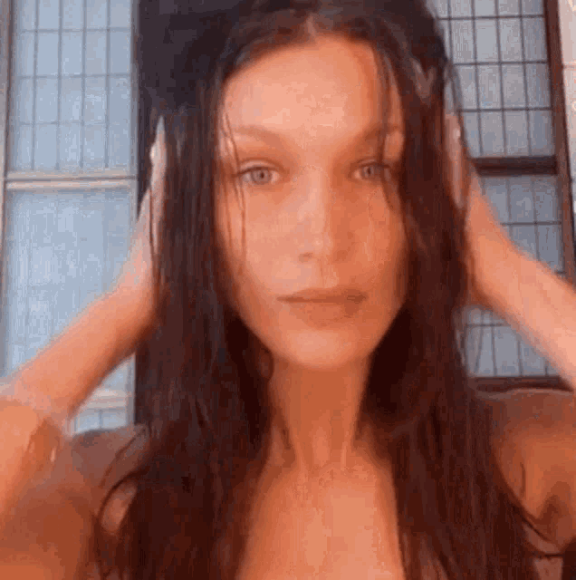 a woman is holding her hair in front of a mirror .