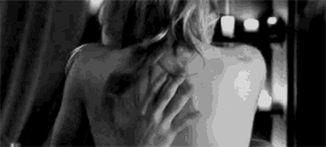 a man is touching a woman 's back with his hand in a black and white photo .