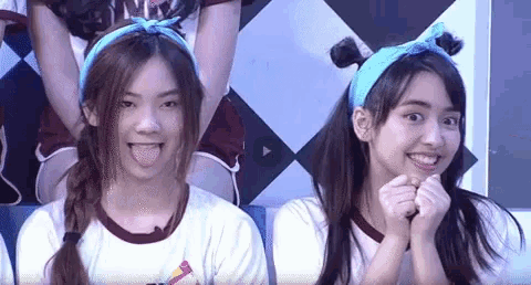 two young women wearing headbands are making funny faces .